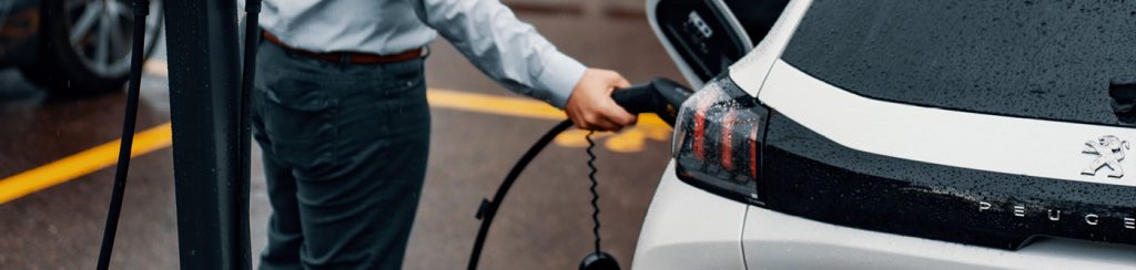 Small business guide to EV charging. A business man is charging his electric vehicle in a car park.