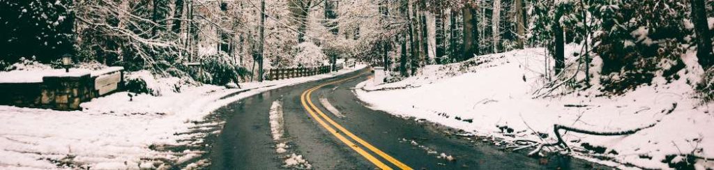 Image of a snow covered landscape with a winding road running through 