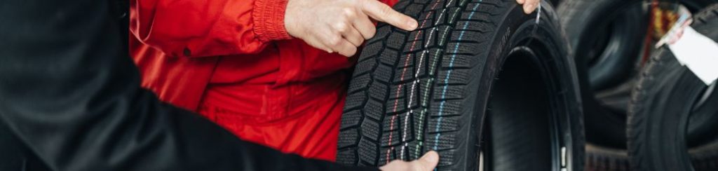 Mechanic showing a customer the difference between EV tyres and regular tyres 